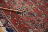 Worn antique Farahan Sarouk rug detail: cherry red pile, intricate vines, palmettes, exposed foundation, frayed edge.