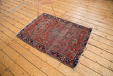 Antique Farahan Sarouk rug displaying navy border, worn cherry red field, delicate palmettes, and tattered edge.
