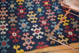 Playful geometric motifs on the antique Karabagh Kilim rug in navy, red, blush, and yellow.