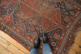 Vintage Qashqai rug with brick red field, geometric border, boteh patterns, and wear.