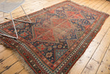 Close-up view of the vintage Qashqai rug's mostly secured side edge with geometric border.