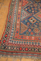 Vintage Qashqai carpet corner detail, displaying geometric borders in brick red, navy blue, and bronze.
