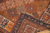 Antique Caucasian runner close-up: guli hennai motif, copper field, navy border, tattered fringe.