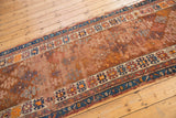 Antique Caucasian runner's geometric pattern, storied wear, and copper, blue, ivory tones.