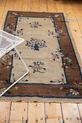 Bronze border, natural beige field, and floating blue, pale mauve floral sprays on a Peking rug.