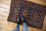Vintage Heriz rug showing geometric floral medallion, patterned border, and tattered ends.