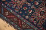 Vintage Heriz rug corner: navy blue field with geometric florals and a wine red serrated leaf border.