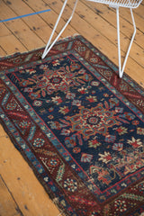 Heriz rug featuring navy field, geometric floral motifs, and wine red serrated leaf border.
