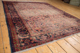 Fringed end of vintage Lilihan rug with faded navy border and intricate worn field.