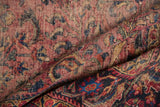 Textured surface of folded hand-knotted Lilihan rug, in dusty raspberry, navy, and gold.