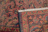 Close view of a vintage Lilihan rug's edge, white fringe, and intricate worn design.