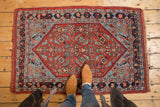 Antique Bijar rug corner: red herati design, navy border, and original side selvage.