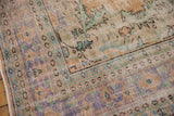 Distressed Oushak rug corner, showing faded apricot, mint, and inky royal blue pile with wear.