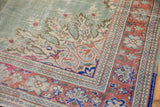Distressed Oushak rug corner with pale mint green field and brilliant blush floral border.