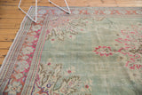 Distressed mint green Oushak carpet corner with vibrant raspberry and blush floral patterns.