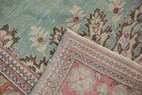 Distressed vintage Oushak rug's folded corner, mint green field, raspberry red border.