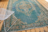 Distressed Oushak rug corner with sky blue field, European Rococo leaves, and visible foundation wear.