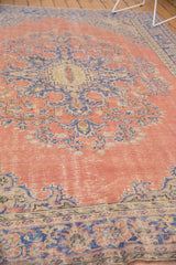 Distressed dusty blush field with pale royal blue European-influenced scrolling floral motifs.