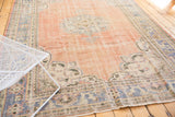 Distressed vintage Oushak rug detail, pale rose field with European spandrel and faded blue border.