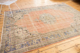 Distressed Oushak rug corner, faded rose field, detailed blue European-style spandrels.