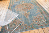 Distressed vintage Oushak carpet pile featuring sky blue and pale apricot scrolling vinery.