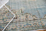 Distressed Oushak border with European scrolling vines in charcoal, mint, and ivory.