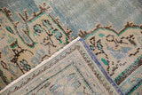 Folded distressed Oushak rug, revealing abrashed blue field, ivory motifs, and worn pile.
