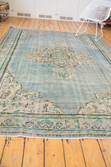 Distressed Oushak carpet showcasing its abrashed powder blue field and faded European design.