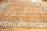 Distressed apricot orange Oushak carpet, highlighting worn texture and subtle floral vinery.