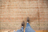 Pale apricot and ivory scrolling vinery on a vintage distressed Oushak carpet with mostly even wear.
