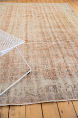 Distressed vintage Oushak rug with faded apricot, ivory pile, even wear, and secured end.