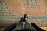Distressed vintage Oushak carpet with worn peach field, mint green, and denim blue border.