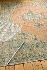 Distressed vintage Oushak rug corner, showing faded peach, blue, and mint green Rococo spandrels.