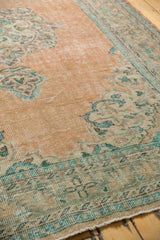 Distressed vintage Oushak carpet with faded peach and mint green Rococo patterns.