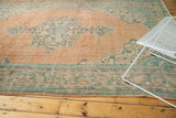 Faded peach, mint green, and blue patterns on the distressed border of a Vintage Oushak rug.