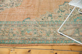 Faded peach, mint green, blue ornamental motifs on a distressed vintage Oushak carpet.