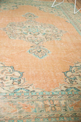 Distressed pile texture of a vintage Oushak rug in faded peach, blue, and mint tones.