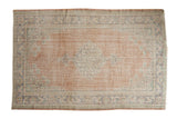 Distressed Oushak carpet with faded red field, roundel medallion, and decorative finials, 5'3