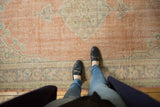 Distressed texture of a vintage Oushak carpet, showing faded red field and blue border.