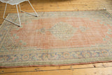 Distressed Oushak rug border with faded blue, pale beige curvilinear motifs.