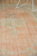 Faded blush and pale beige tones on distressed vintage Oushak rug with even wear.