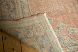 Corner of vintage distressed Oushak carpet, showing worn pile and hand-knotted patterned reverse.