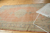 Distressed Oushak rug's faded red field with muted blue border patterns and visible wear.