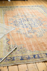 Distressed Oushak rug corner showing dusty apricot field, faded blue motifs and even wear.