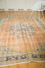 Distressed Oushak rug corner, showing faded blue border, apricot field, and even wear.