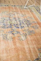 Distressed Oushak rug texture: visible knot heads, faint foundation, apricot blush, faded royal blue.
