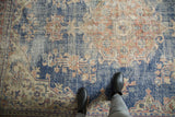 Navy blue distressed Oushak rug section, antique ivory and pale terracotta floral motifs.