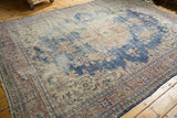 Distressed vintage Turkish Oushak rug showing navy blue field, worn floral sprays, and terracotta border.