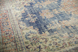 Worn navy blue and ivory distressed Oushak rug with pale terracotta floral motifs.