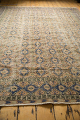 Distressed Oushak rug's low pile, dusty apricot and pale navy medallion lattice, geometric border.